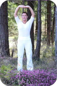 Femme pratiquant le Qi Gong, les bras levés en l'air